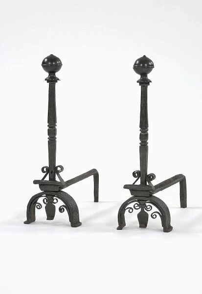 Fire dogs. One of a pair of wrought iron fire dogs with turned brass finials, arched legs