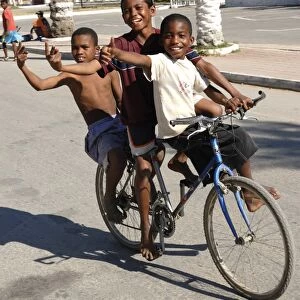 Happy boys cycling through the streets of Toliara, Madagascar, Africa