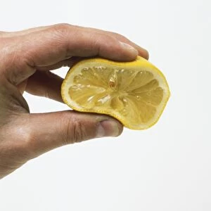 Hand squeezing a halved lemon