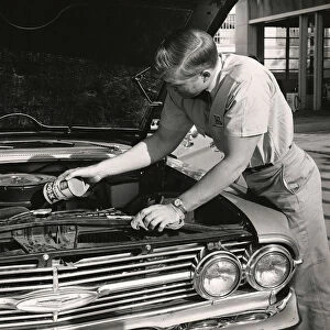 Worker adding oil to car