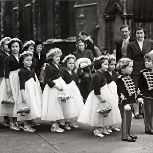 Two boys tressed as toy soldiers marshalling a long line of bridesmaids outside St