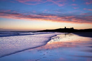 Forts Collection: Looking across Embleton Bay at sunrise towards the silhouetted ruins of Dunstanburgh Castle in