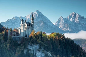 German Culture Collection: Neuschwanstein Castle surrounded by colorful woods and snowy peaks, Fussen, Bavaria