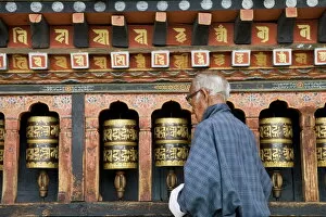 Temples Photo Mug Collection: Old Bhutanese man turning prayer wheels in Buddhist temple, Thimphu, Bhutan, Asia
