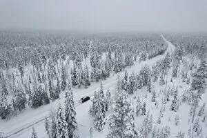 Public Land Collection: View from above of a car travelling icy road in the middle of the frozen forest covered with snow