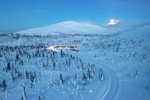Winding Road Collection: Aerial view of a snowy mountain road in the frozen forest nearby a ski area at dusk