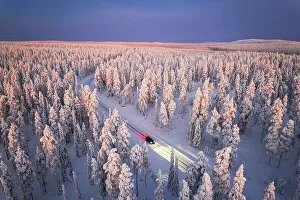 Finland Premium Framed Print Collection: Car traveling on icy road crossing the winter forest covered with snow from above, Lapland, Finland
