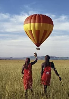 African Tribe Collection: Two Msai warriors watch a hot air balloon flight over Masai Mara