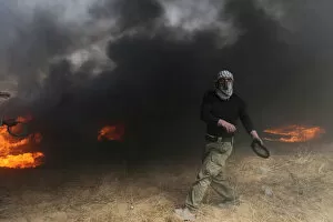 Protestor Collection: Demonstrator passes by burning tires during clashes with Israeli troops at a protest