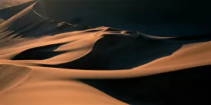 Abstract art Collection: Namibia, Namib Desert, Setting sun lights curving sand dunes near coastal city of