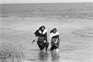 Wading Collection: LONG ISLAND: CLAMMING, 1957. Two nuns in habits, clam digging in the water off of Long Island