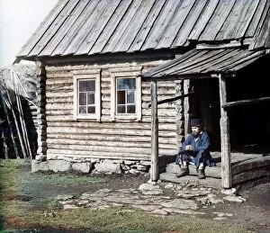 12 May 2010 Glass Coaster Collection: RUSSIA: LOG CABIN, 1910. A Bashkir man sitting on the steps of a log cabin in the