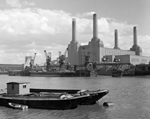 Chimneys Collection: A ship unloading at the pier at Battersea Power Station, seen from across the Thames