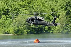 Utility Helicopters Collection: A UH-60 Blackhawk helicopter fills a suspended water bucket in Marquette Lake, Pennsylvania