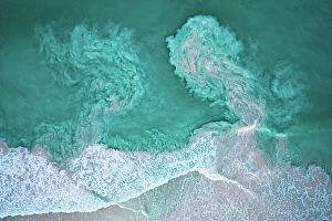 Swirling Collection: Waves crashing on beach and carrying sediments back out to sea, aerial view. The Bahamas