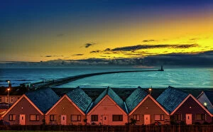 Illuminate Collection: Row of Houses illuminated at sunset with Roker Pier Lighthouse in the distance, Sunderland, England