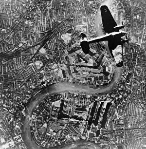 The London Blitz Photographic Print Collection: A Heinkel 111 bomber aircraft of the German Luftwaffe flies over Tower Bridge